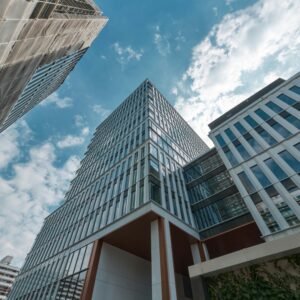 Low-angle view of modern glass office buildings against a partly cloudy blue sky in an urban setting.